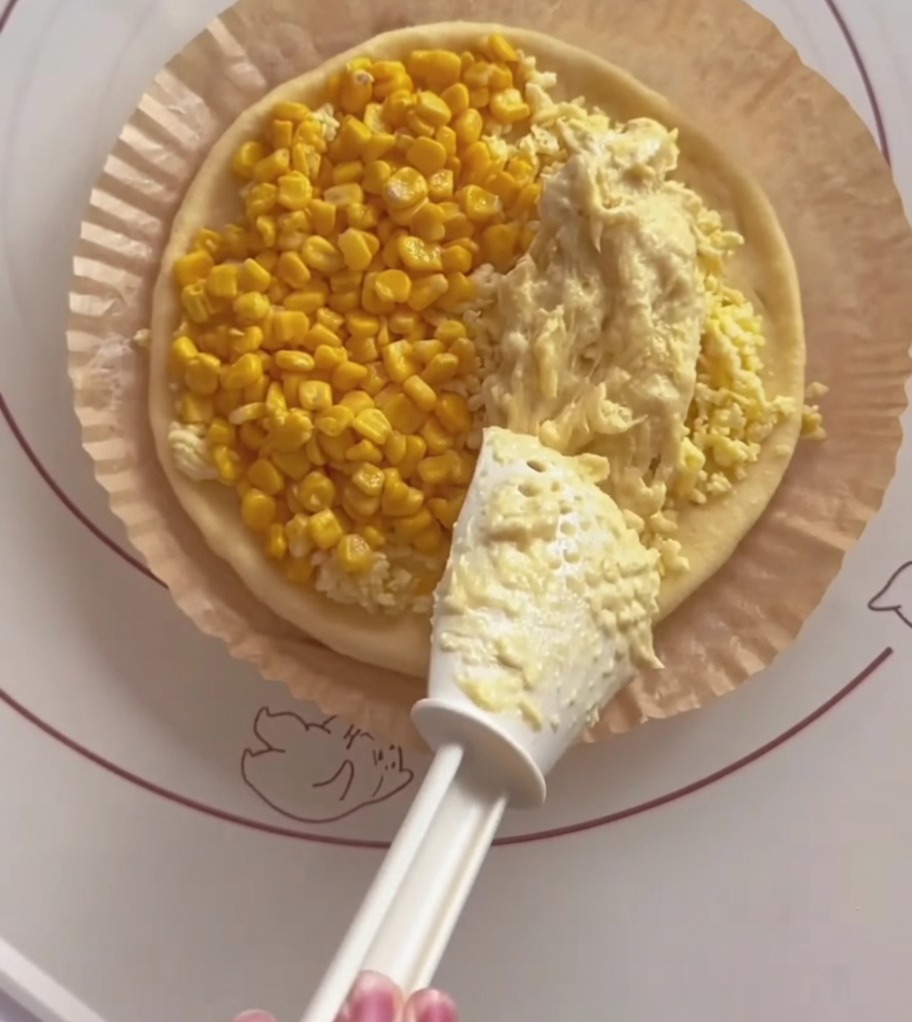 Espátula blanca extendiendo pasta de durián sobre la otra mitad de la base.