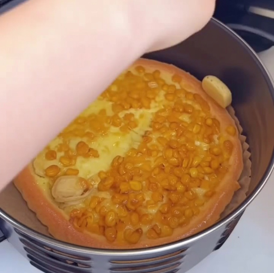 Mano usando una brocha pequeña para aplicar aceite al borde dorado de la pizza.