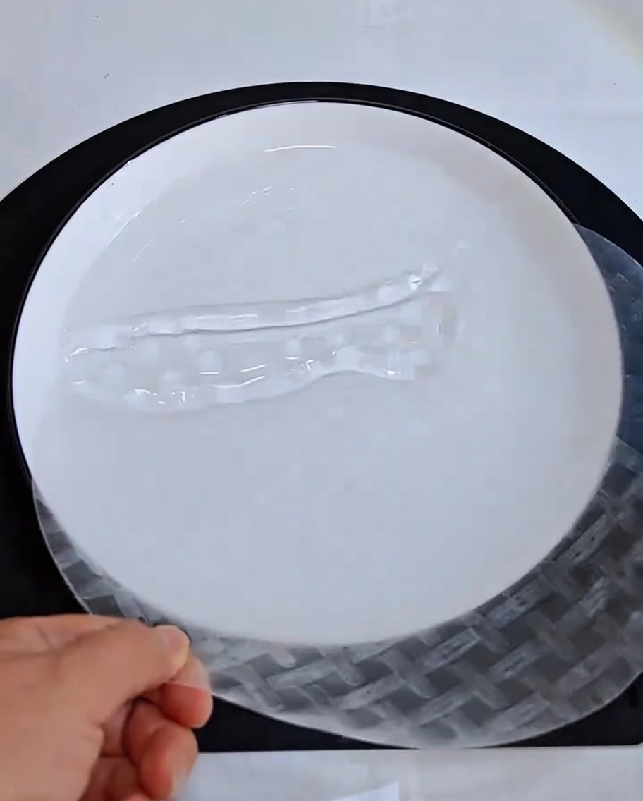 Una mano sumergiendo una lámina de papel de arroz seca en un tazón con agua.