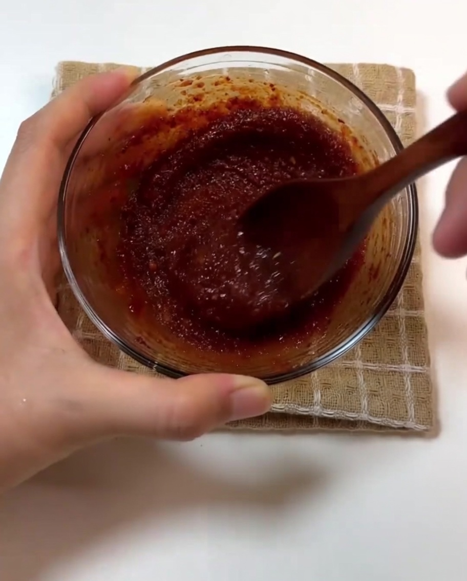 Salsa y dientes de ajo enteros añadiéndose a la panceta cocinada.