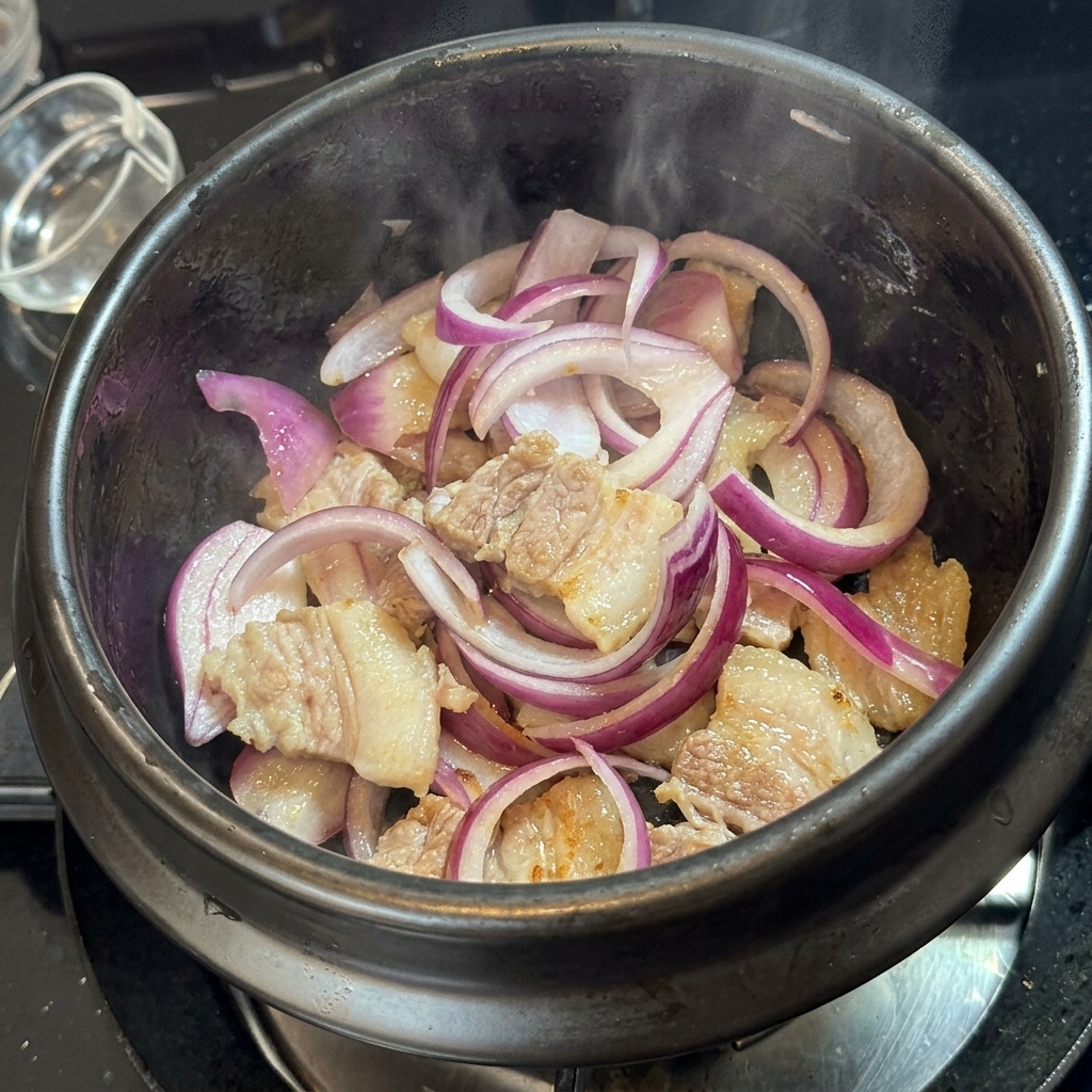 Kimchi mezclado con la carne y la cebolla en la olla de piedra.