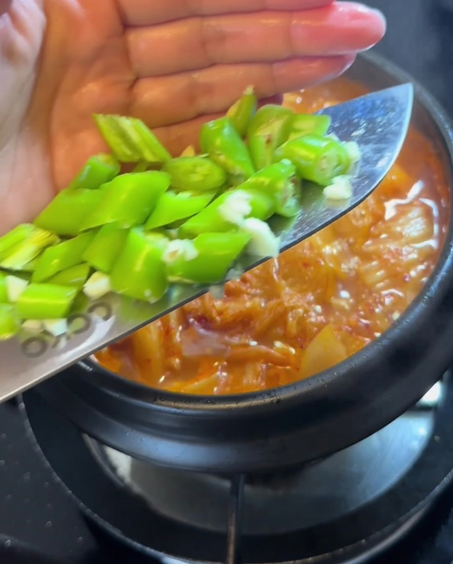 Trozos de chile verde fresco siendo añadidos al estofado hirviendo.