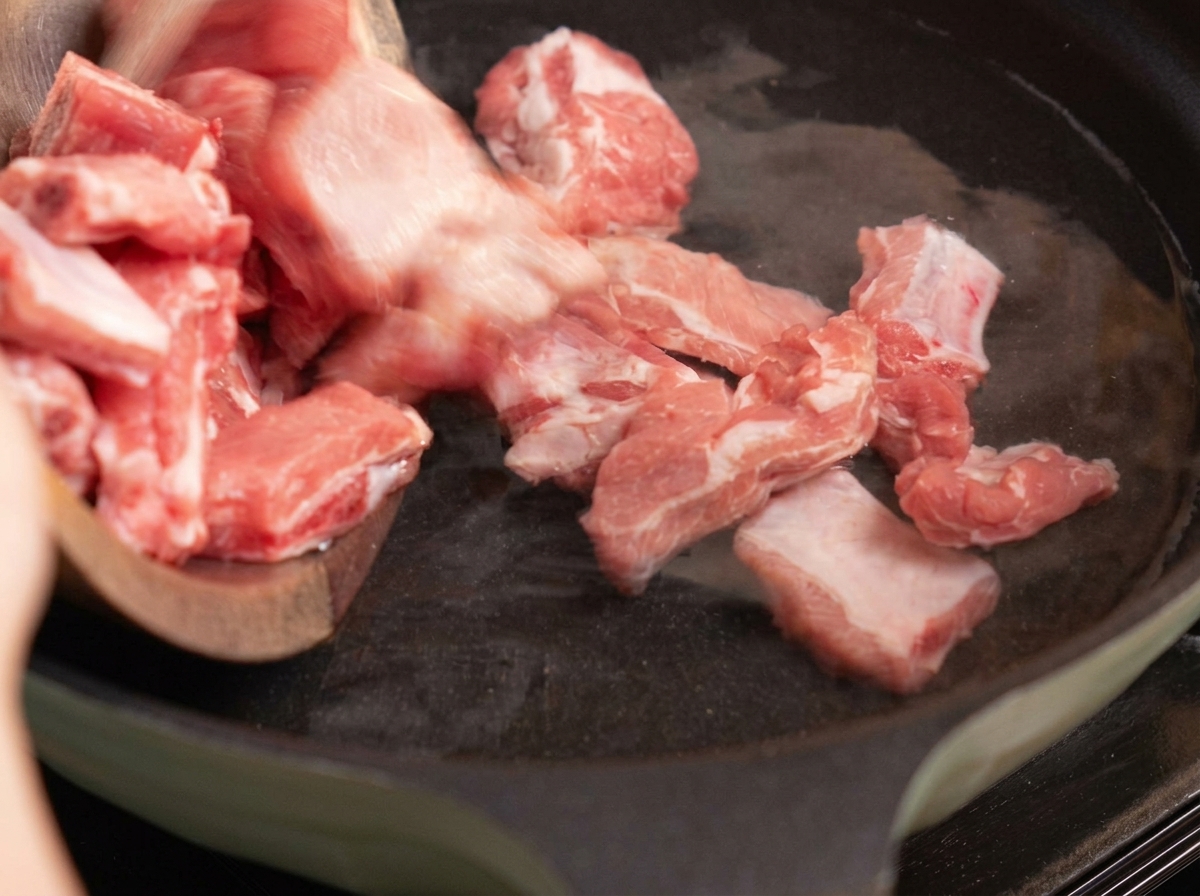 Costillas de cerdo escaldándose en una olla con agua, jengibre y cebollinos.