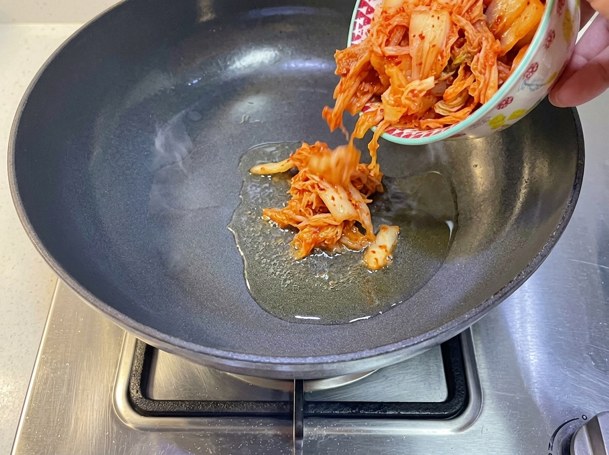 Kimchi coreano siendo vertido en una sartén con aceite caliente.