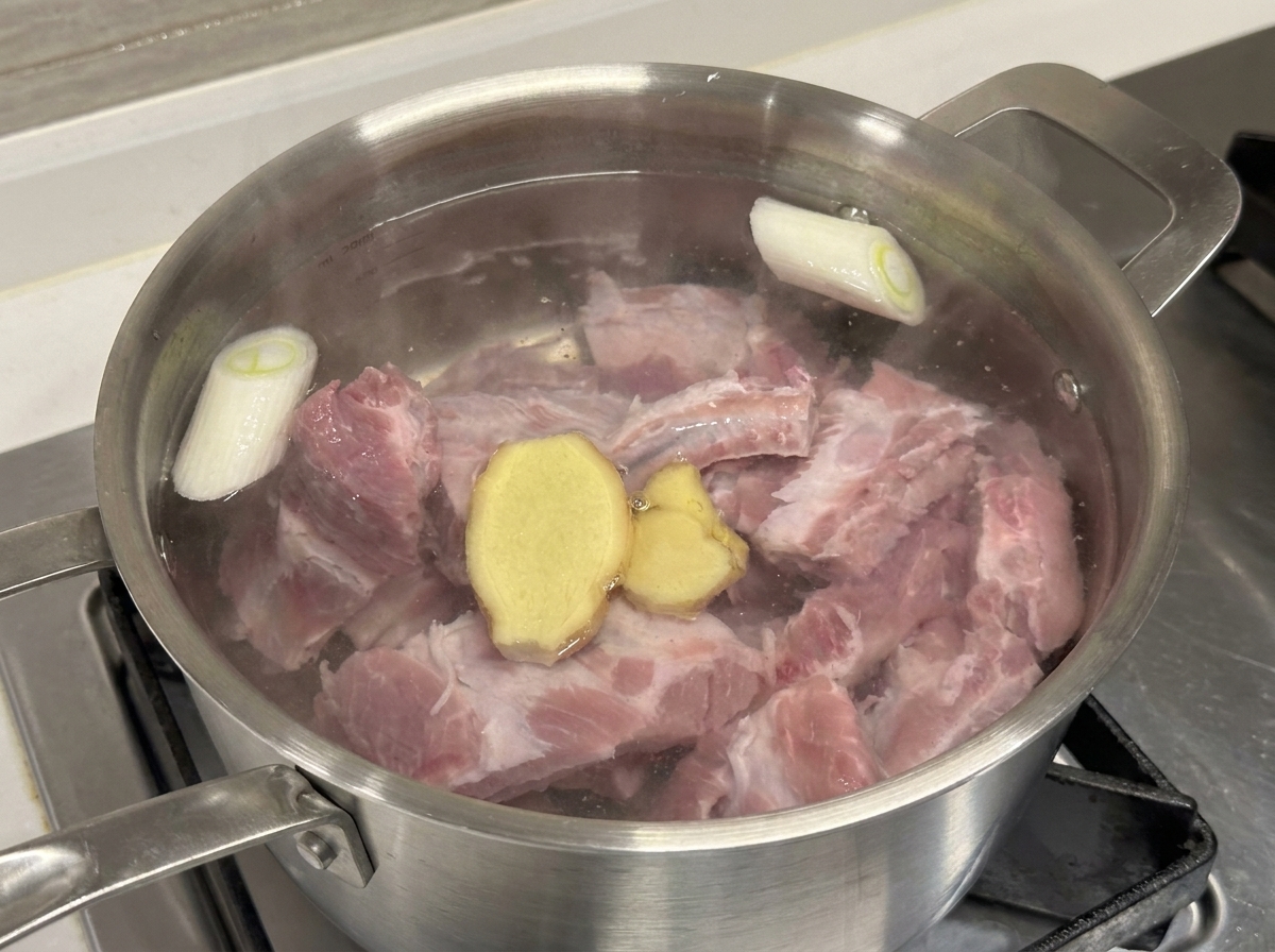 Olla con costillas, cebolleta y jengibre al añadir el vino de cocina.