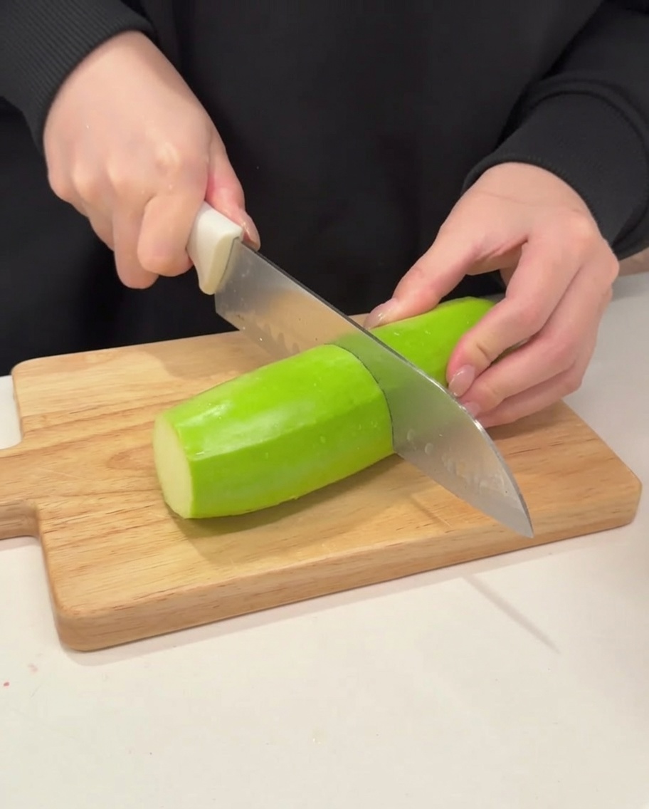 Cuchillo cortando calabacín verde en medias lunas.