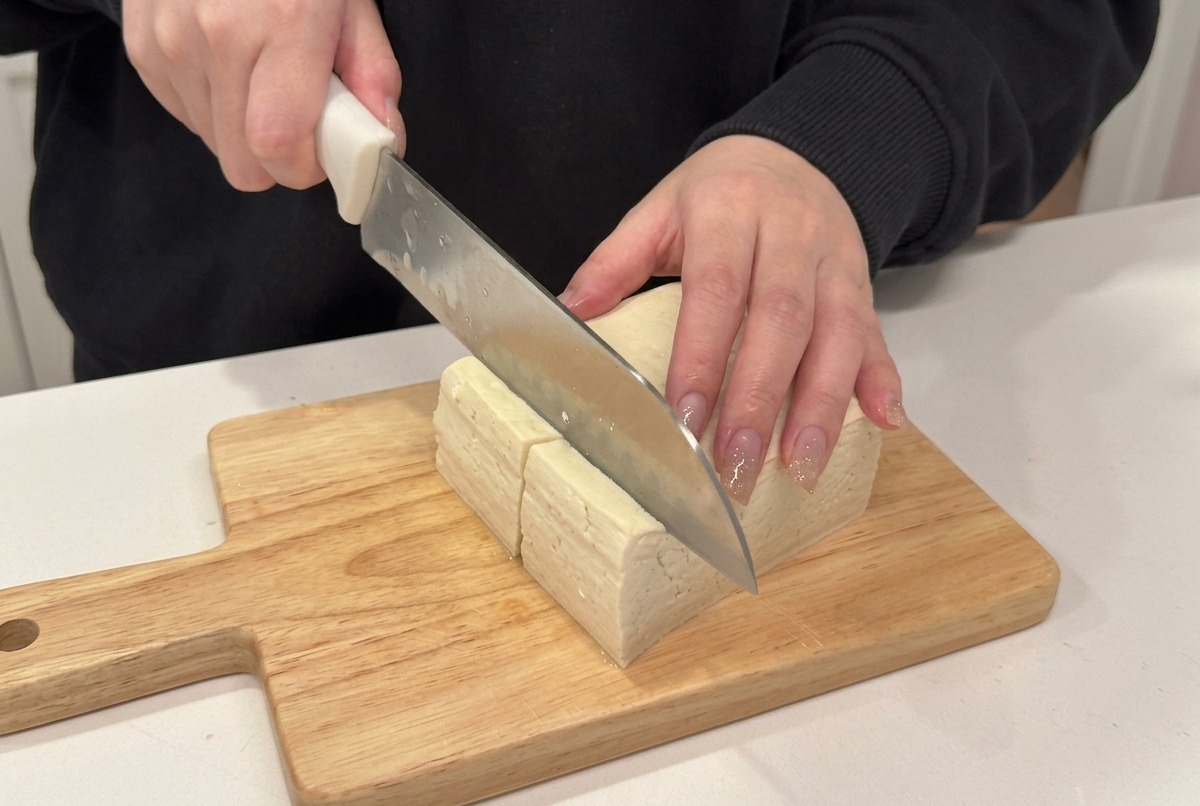 Cuchillo cortando tofu firme en cubos.