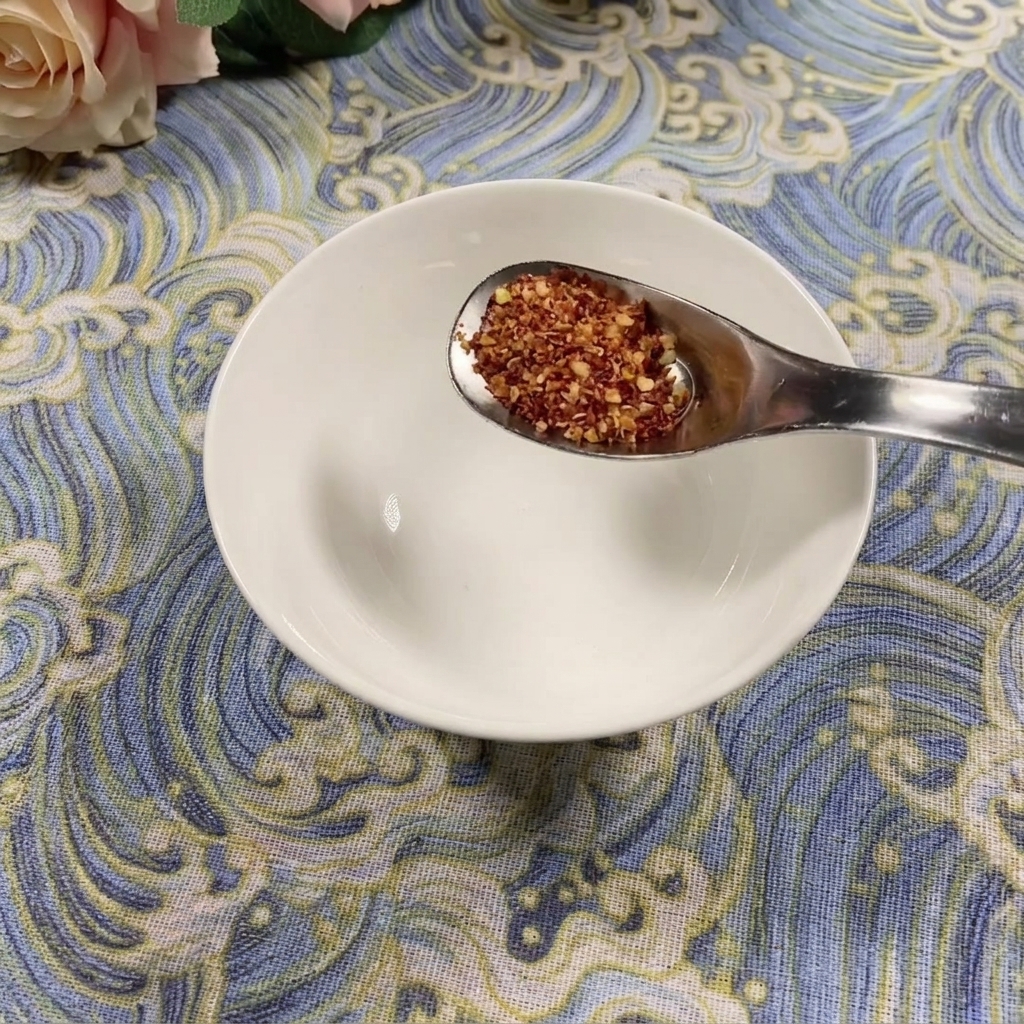 Una cucharada de chile en polvo grueso sobre un tazón blanco vacío.