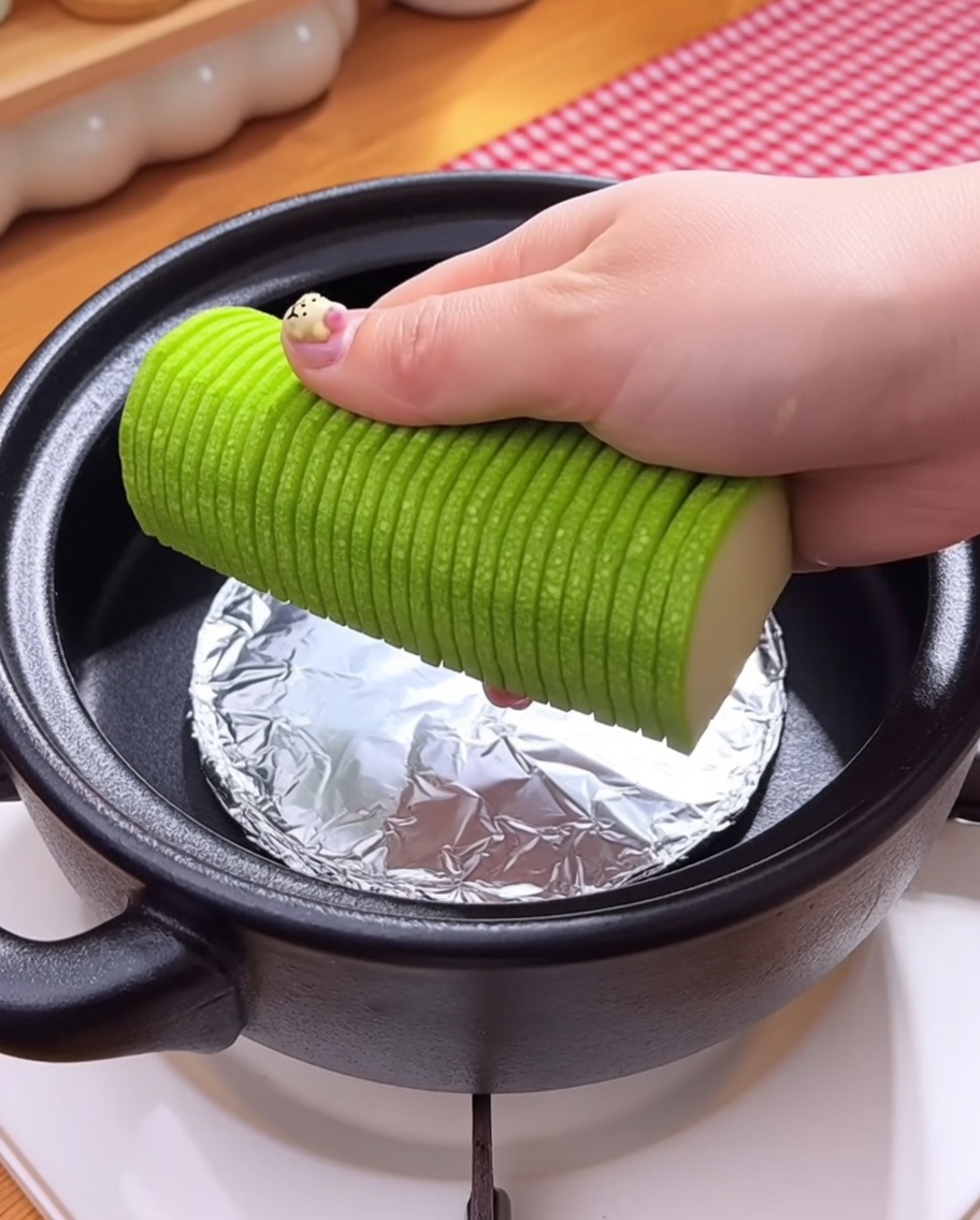 Setas enoki y almejas crudas agregándose a la olla sobre la capa de verduras.