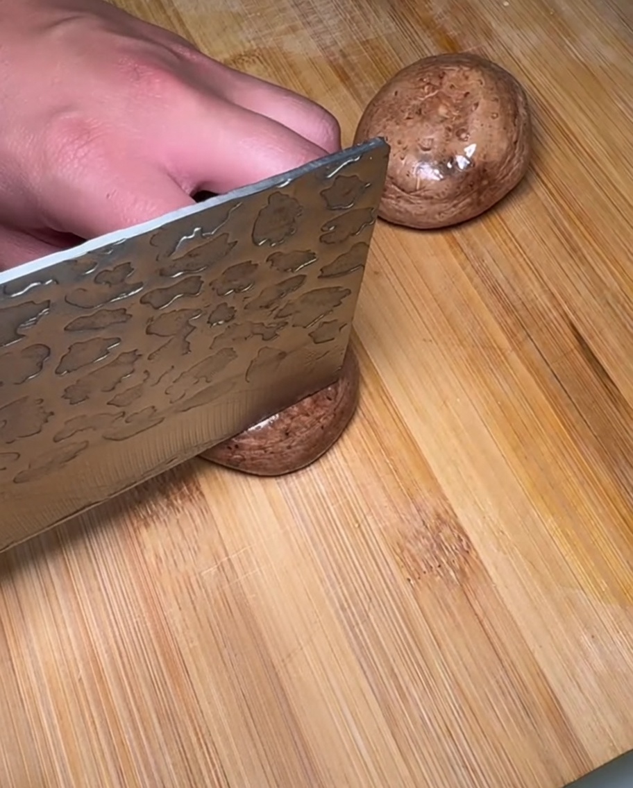 Setas shiitake crudas recién cortadas y amontonadas sobre una tabla de cortar de madera.
