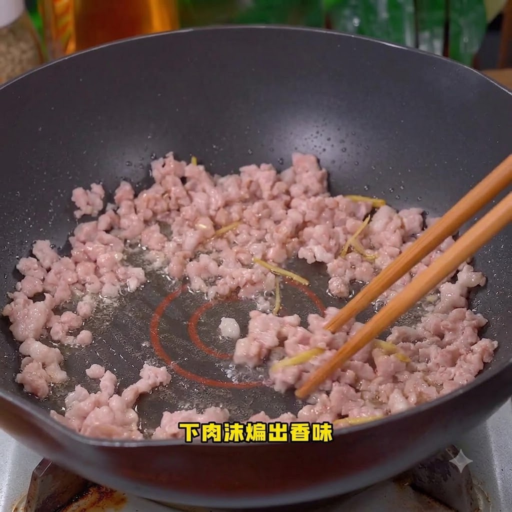 Carne de cerdo picada cocinándose y removiéndose en el wok.