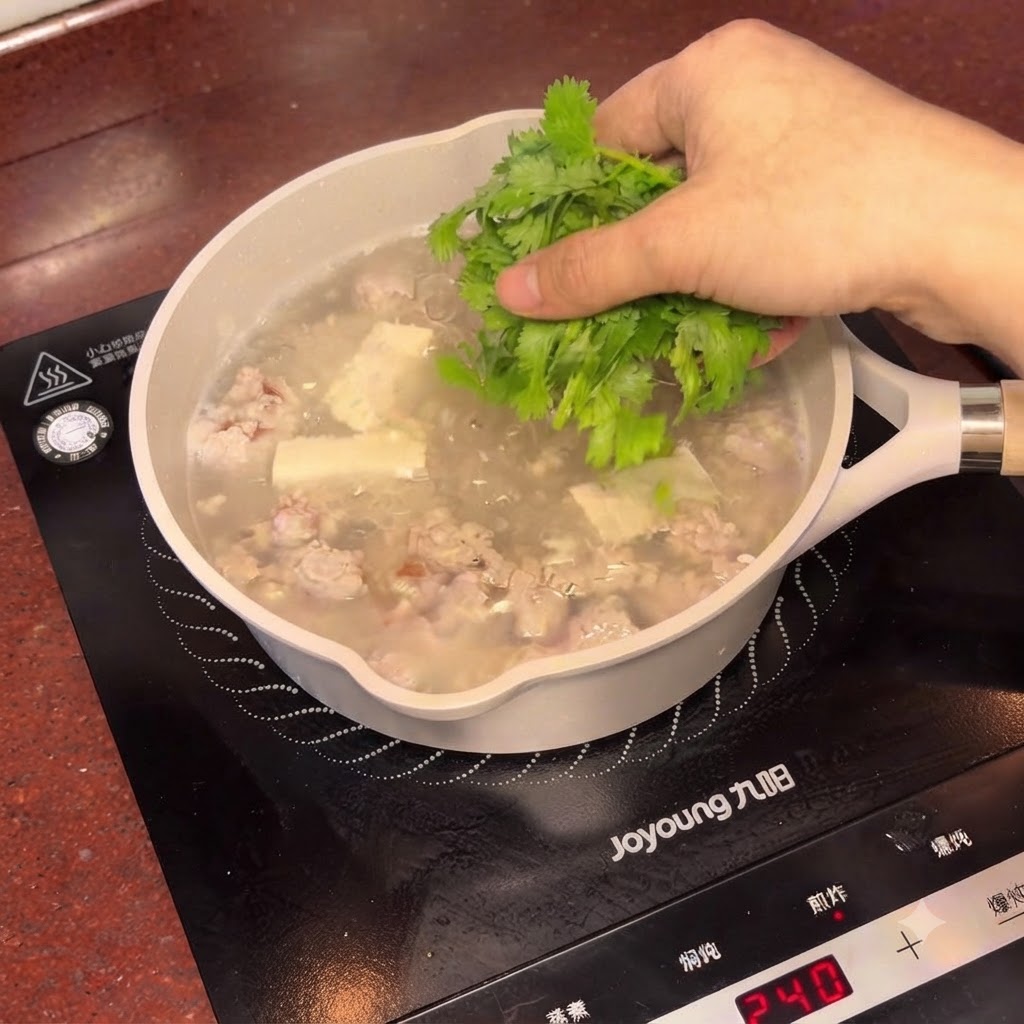 Cilantro fresco picado siendo espolvoreado sobre la olla humeante de sopa de tofu y ciruela.