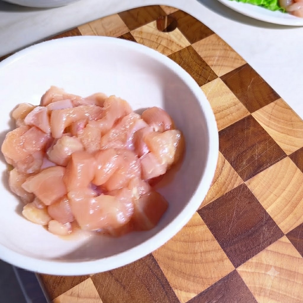 Trozos de pollo crudo en un tazón blanco cubiertos con especias y aceite de oliva.