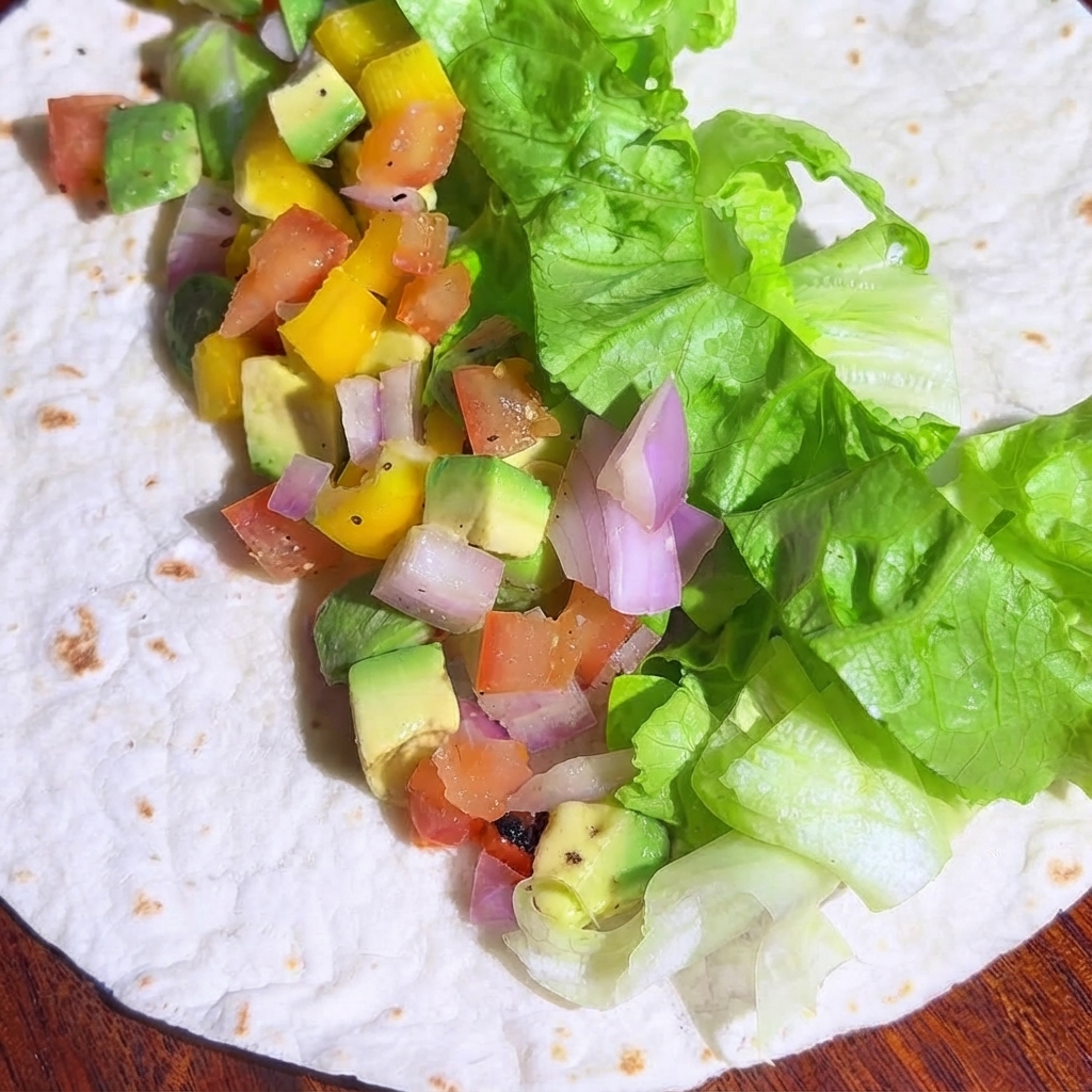 Trozos de pollo cocinado repartidos sobre el relleno de vegetales en la tortilla.