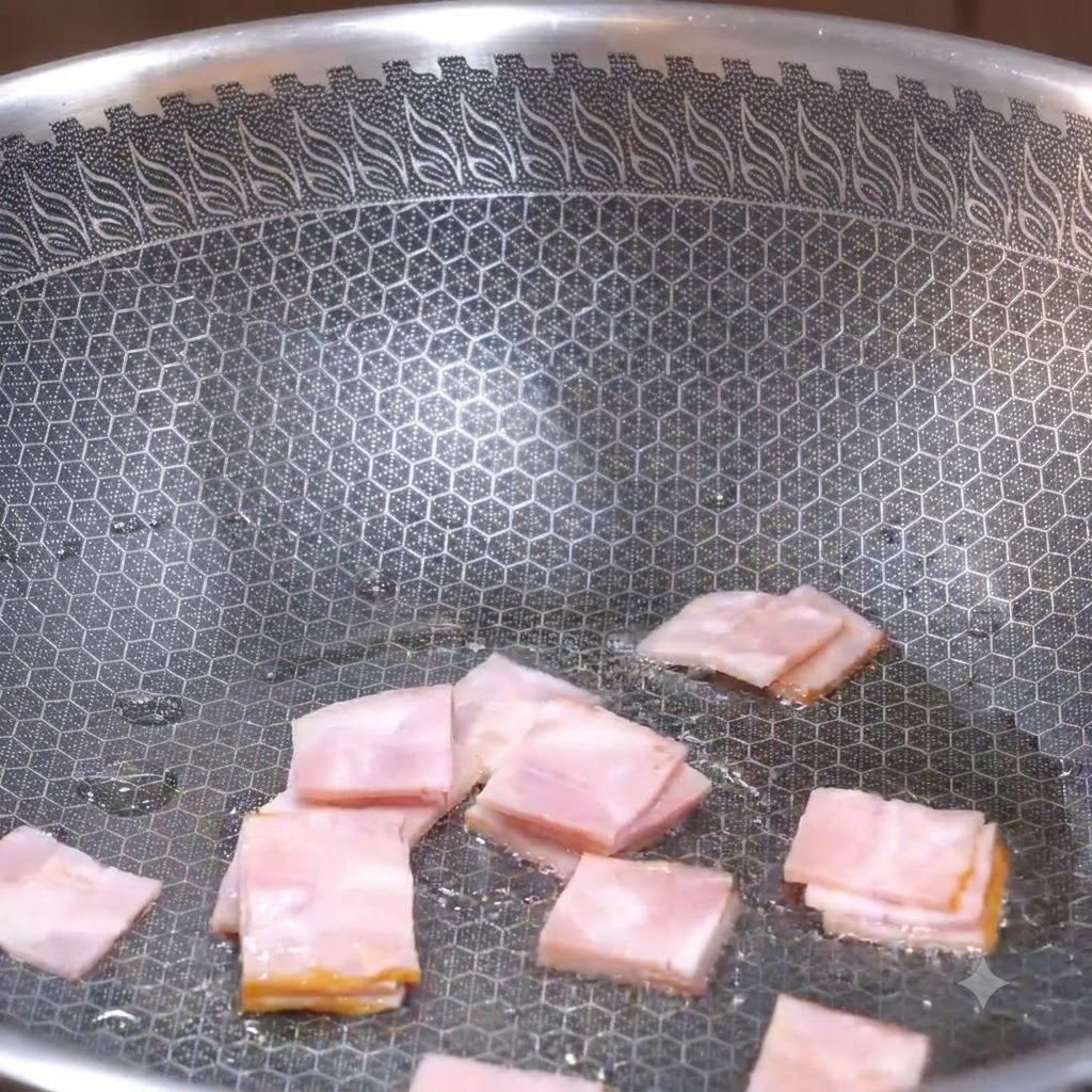 Piezas cuadradas de tocino siendo freídas en un wok texturizado hasta que comienzan a dorarse.