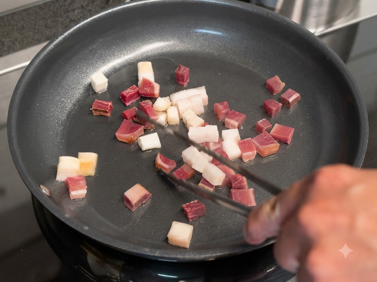 Dados de tocino y carne curada friéndose en una sartén y siendo girados con pinzas de metal.