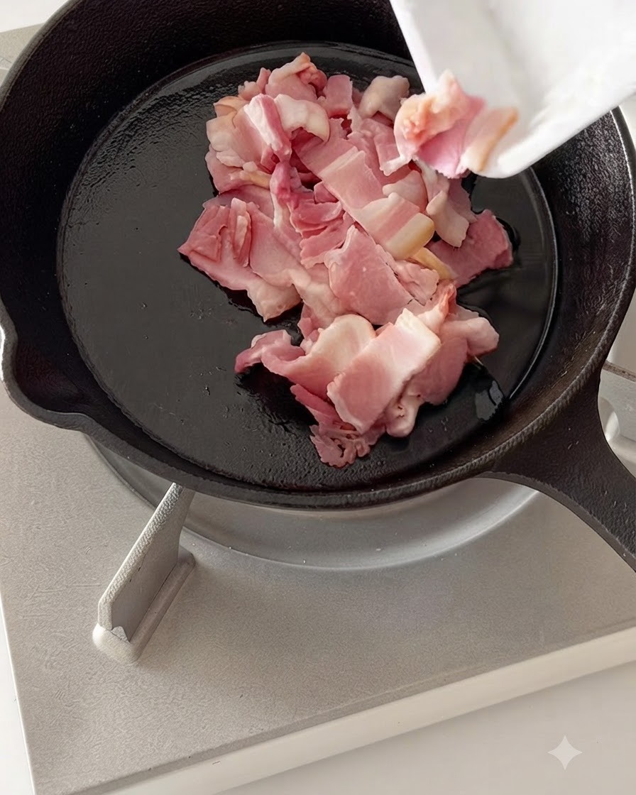 Trozos de beicon picado friéndose en una sartén caliente de hierro fundido.