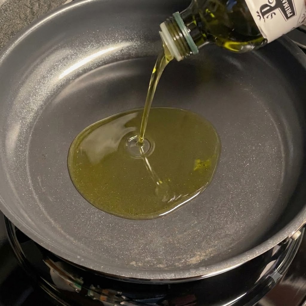 Aceite de oliva vertido en una sartén para freír ajo en rodajas.