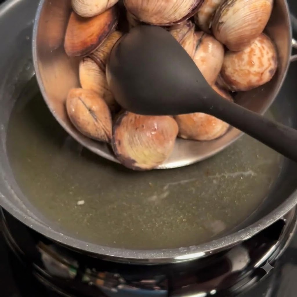 Almejas limpias vertidas desde un bol en una sartén con aceite de ajo.