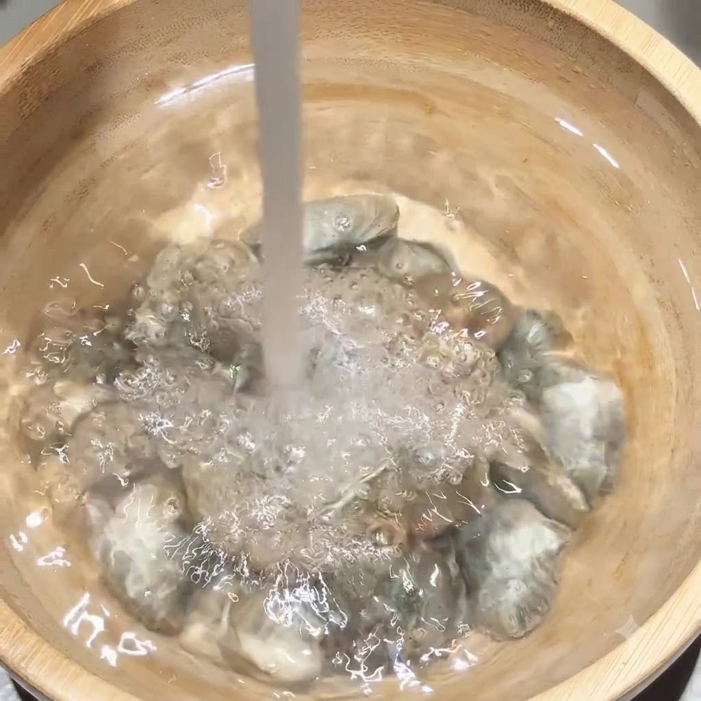 Agua limpia cayendo directamente sobre un lote de almejas dentro de un bol de madera.