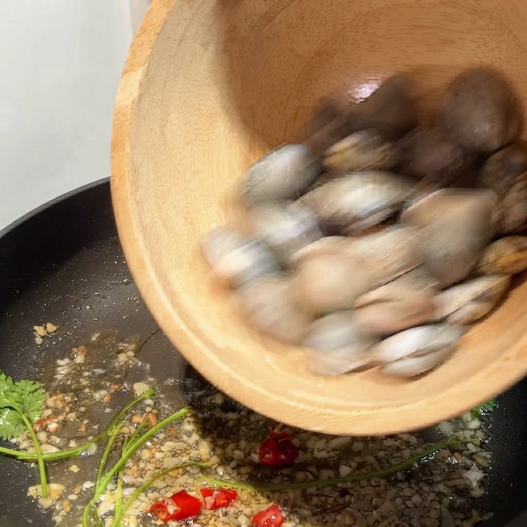 Almejas siendo vertidas desde un bol de madera en una sartén con ajo y guindilla sofritos.