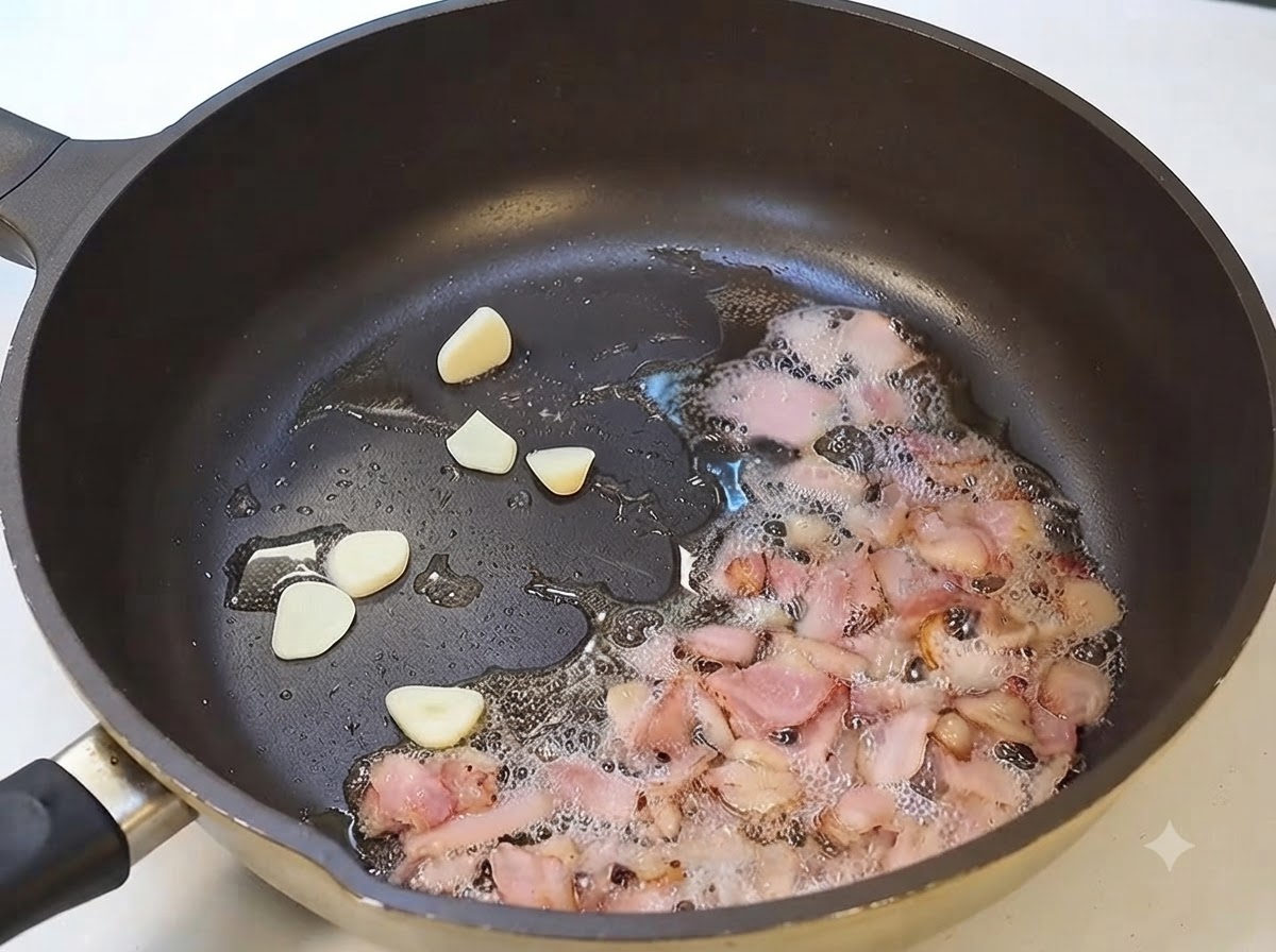 Rodajas de ajo y tocino fritindiéndose juntas en una sartén.