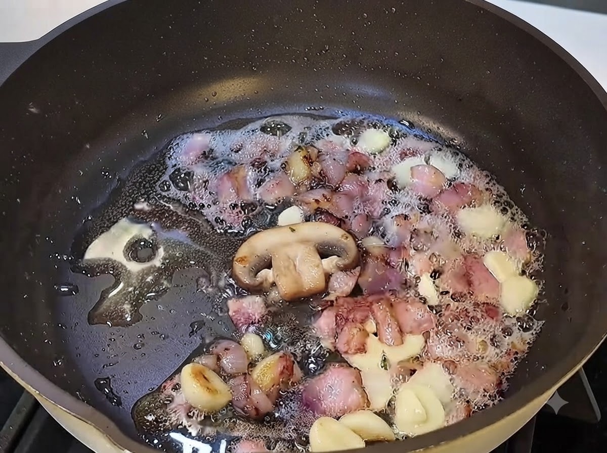 Champiñones en rodajas cocinándose en la sartén junto con el tocino y el ajo.