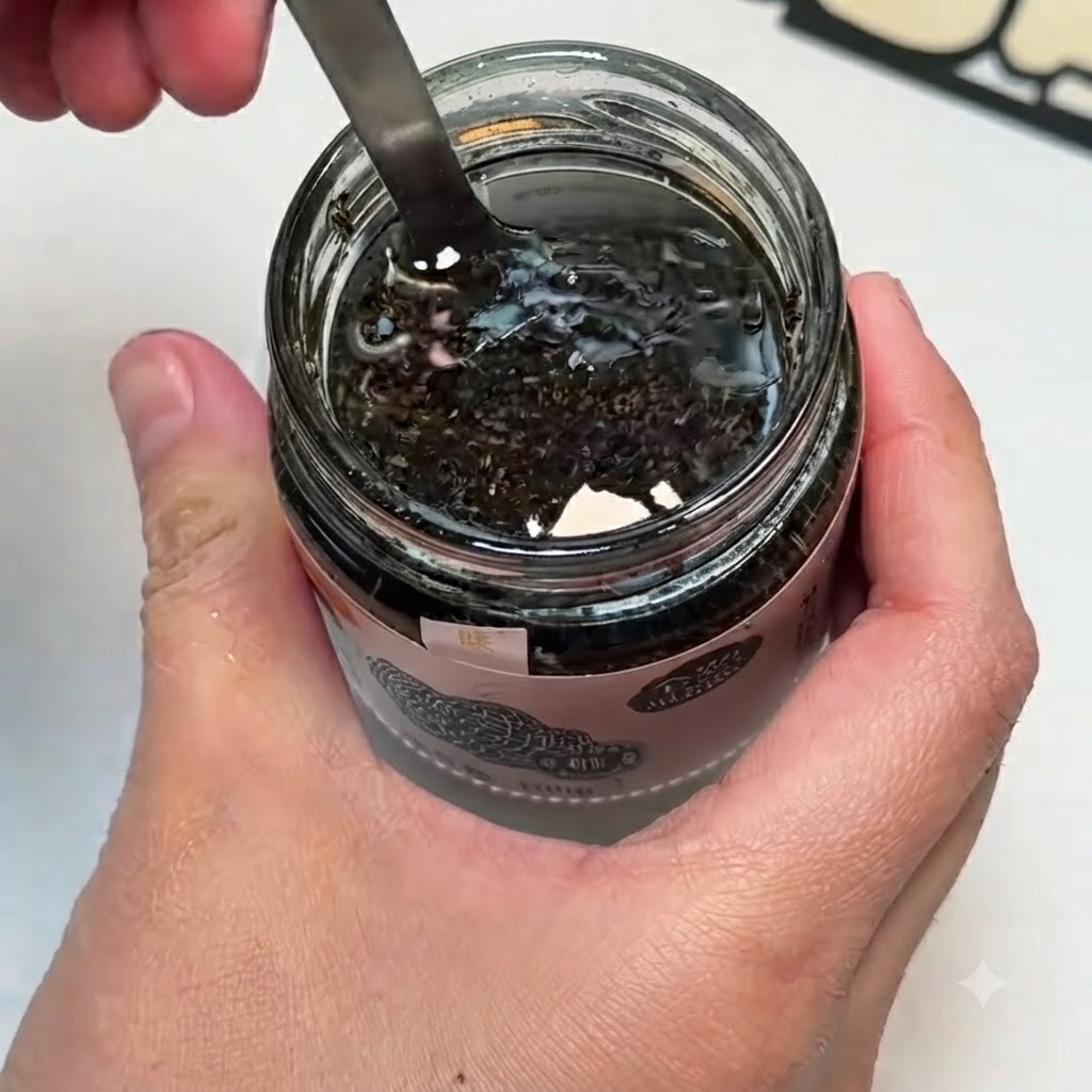 Un tazón pequeño que contiene salsa de trufa negra, yemas de huevo y sal mezclándose con una cuchara.