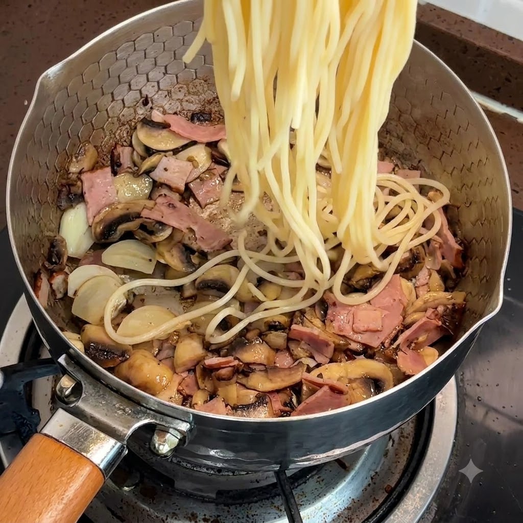 Fideos de espagueti cocidos siendo añadidos a la sartén con tocino y champiñones.