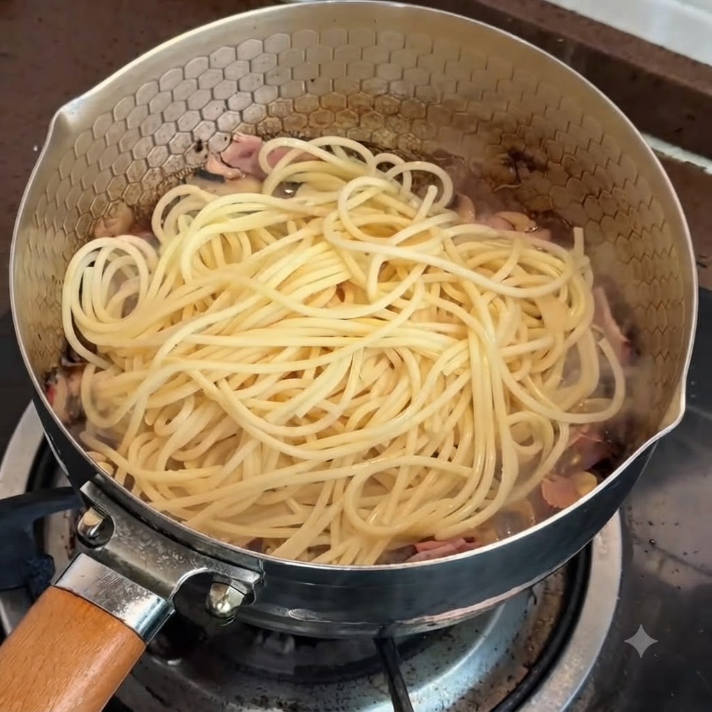 Pasta en una sartén lista para mezclarse con la salsa de trufa y yema de huevo.