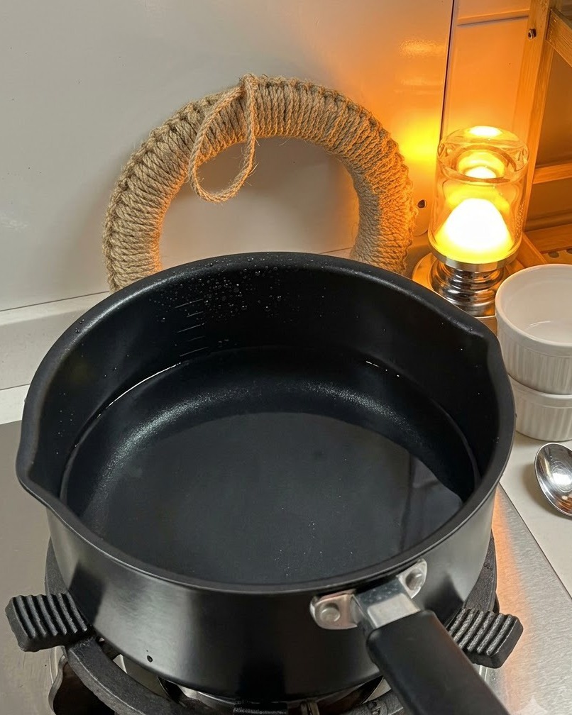 Pasta fusilli seca siendo agregada a una olla con agua hirviendo en la estufa.