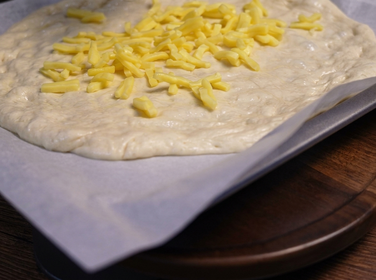Champiñones salteados colocados sobre la capa de queso en la masa de pizza.