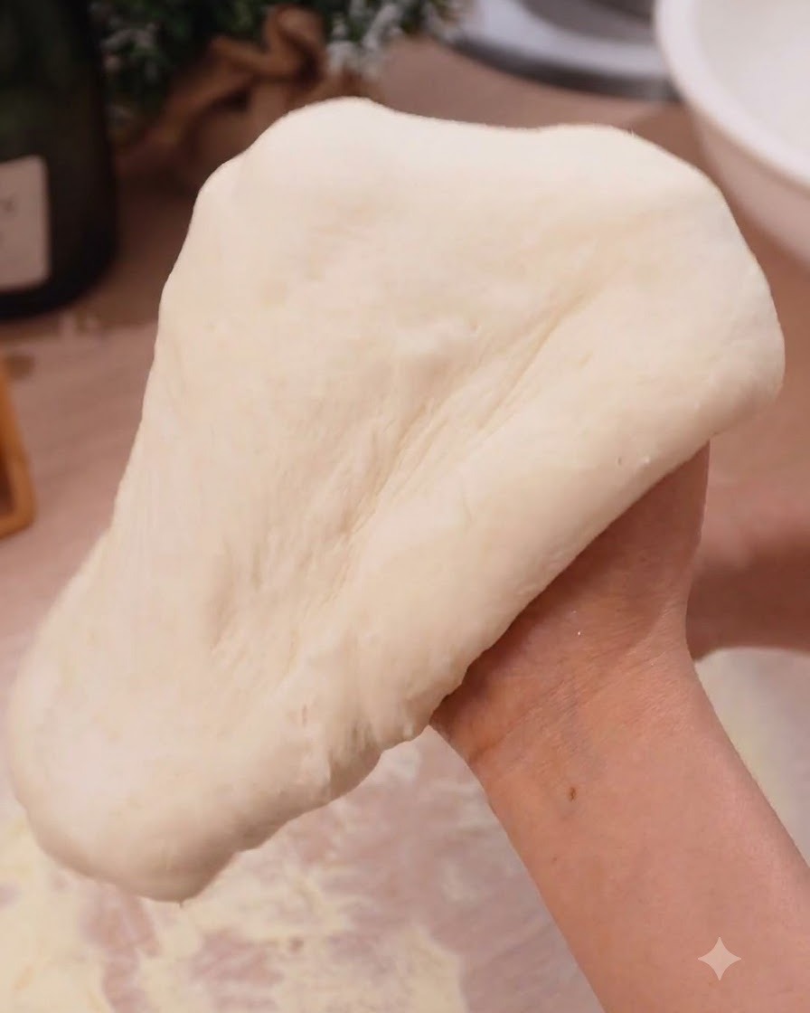 Masa de pizza siendo estirada suavemente sobre los puños cerrados en un entorno de cocina.