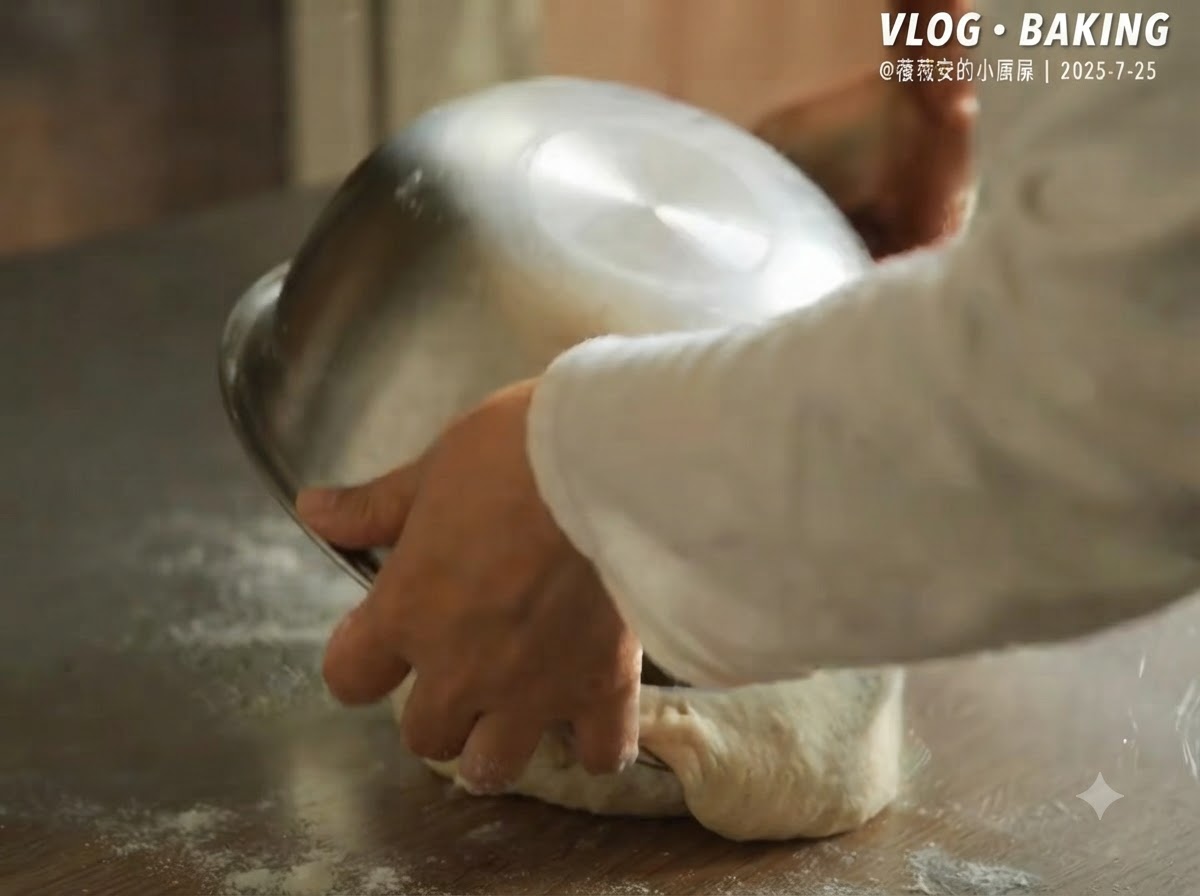 Un tazón de metal siendo volteado para liberar la masa de pizza fermentada sobre una encimera enharinada.