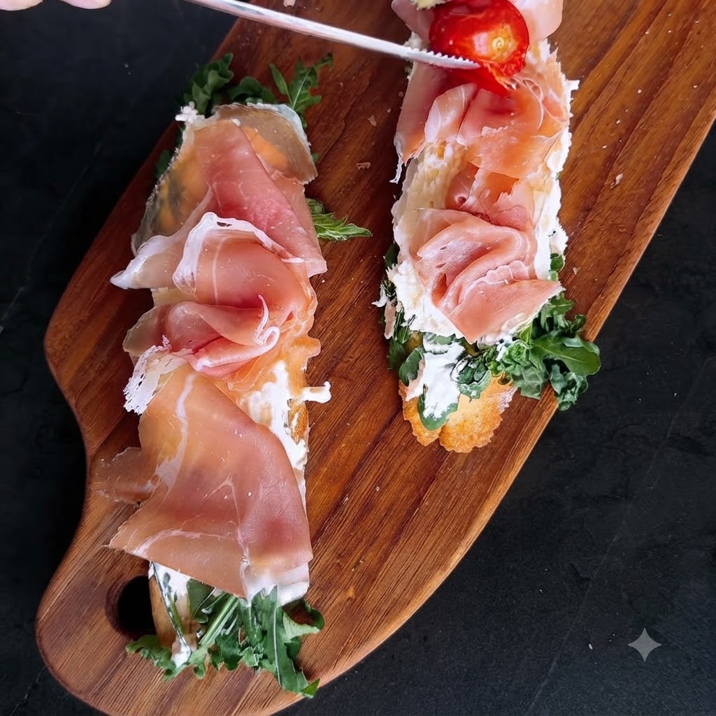 Unas pinzas colocando tomates cherry asados de colores vibrantes sobre las tapas de jamón y queso ya montadas.