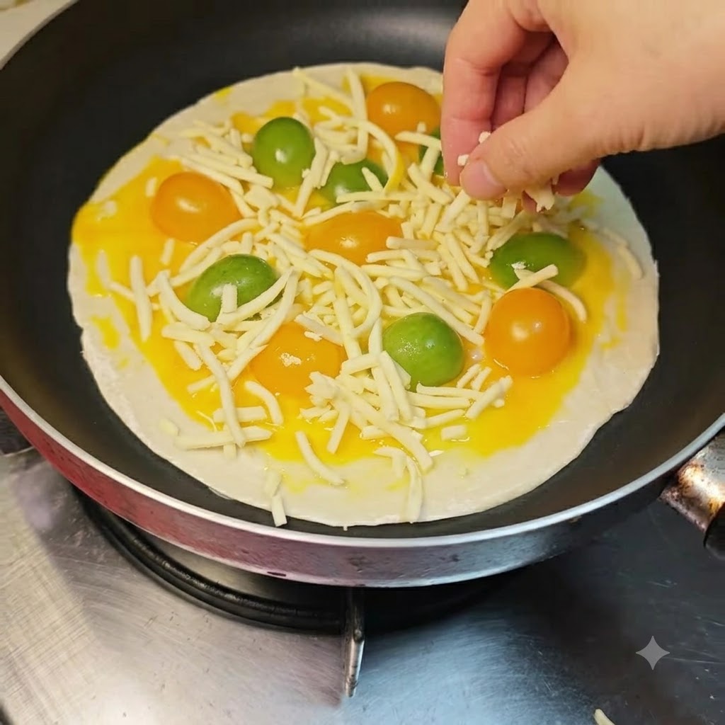 Queso mozzarella rallado siendo espolvoreado a mano sobre los tomates y la capa de huevo.