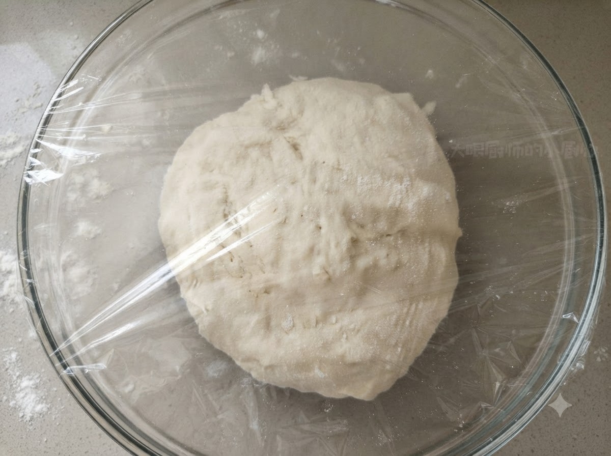 Una bola de masa lisa dentro de un tazón de vidrio transparente cubierto firmemente con plástico transparente.
