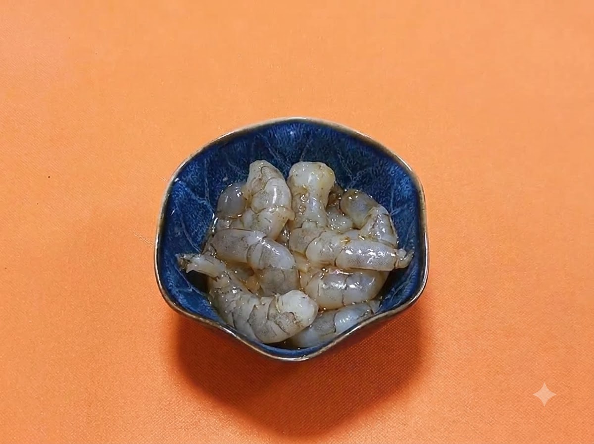 Camarones crudos pelados reposando en un tazón azul oscuro con un adobo brillante de salsa de soya oscura y especias.