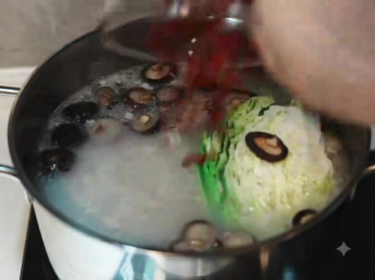 Revidiendo caldo de cerdo opaco y hirviendo con un cucharón blanco después de incorporar col, zanahorias en rodajas, hongos shiitake y bayas de goji.
