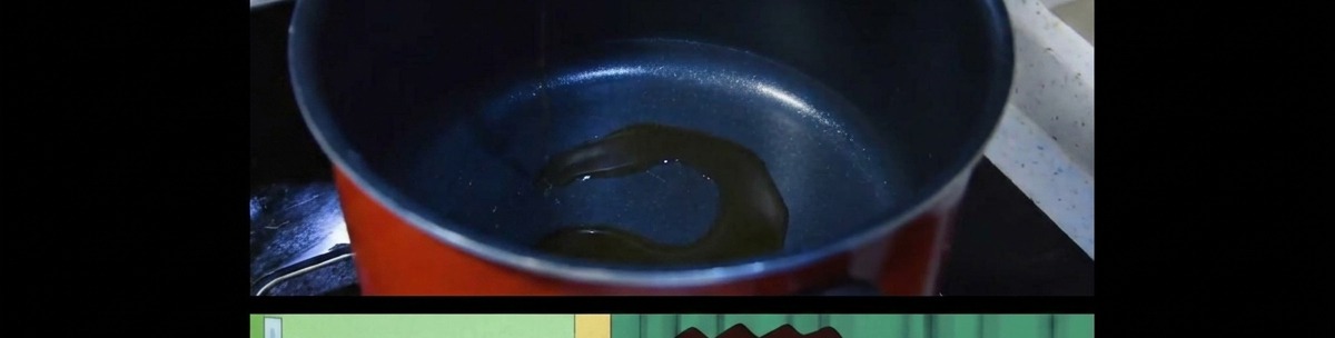 Una capa fina de aceite de sésamo calentándose en el fondo de una olla de cocina oscura.