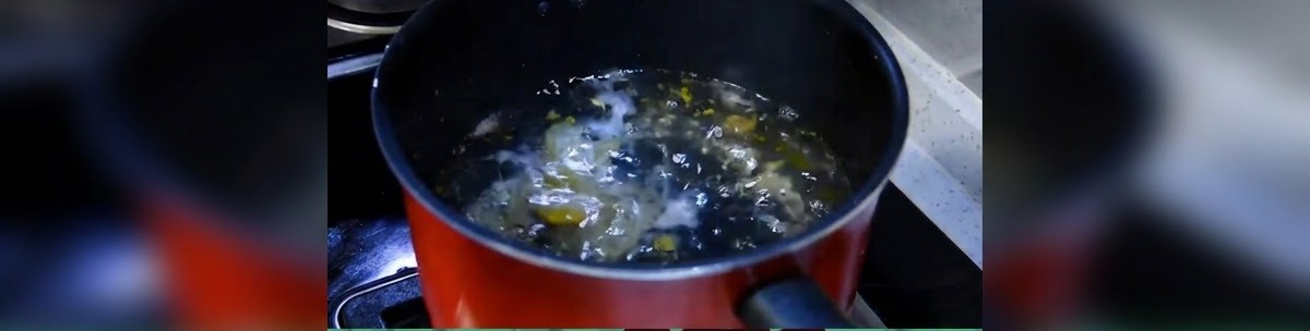Una olla de cocina oscura con agua hirviendo a fuego lento en la estufa.