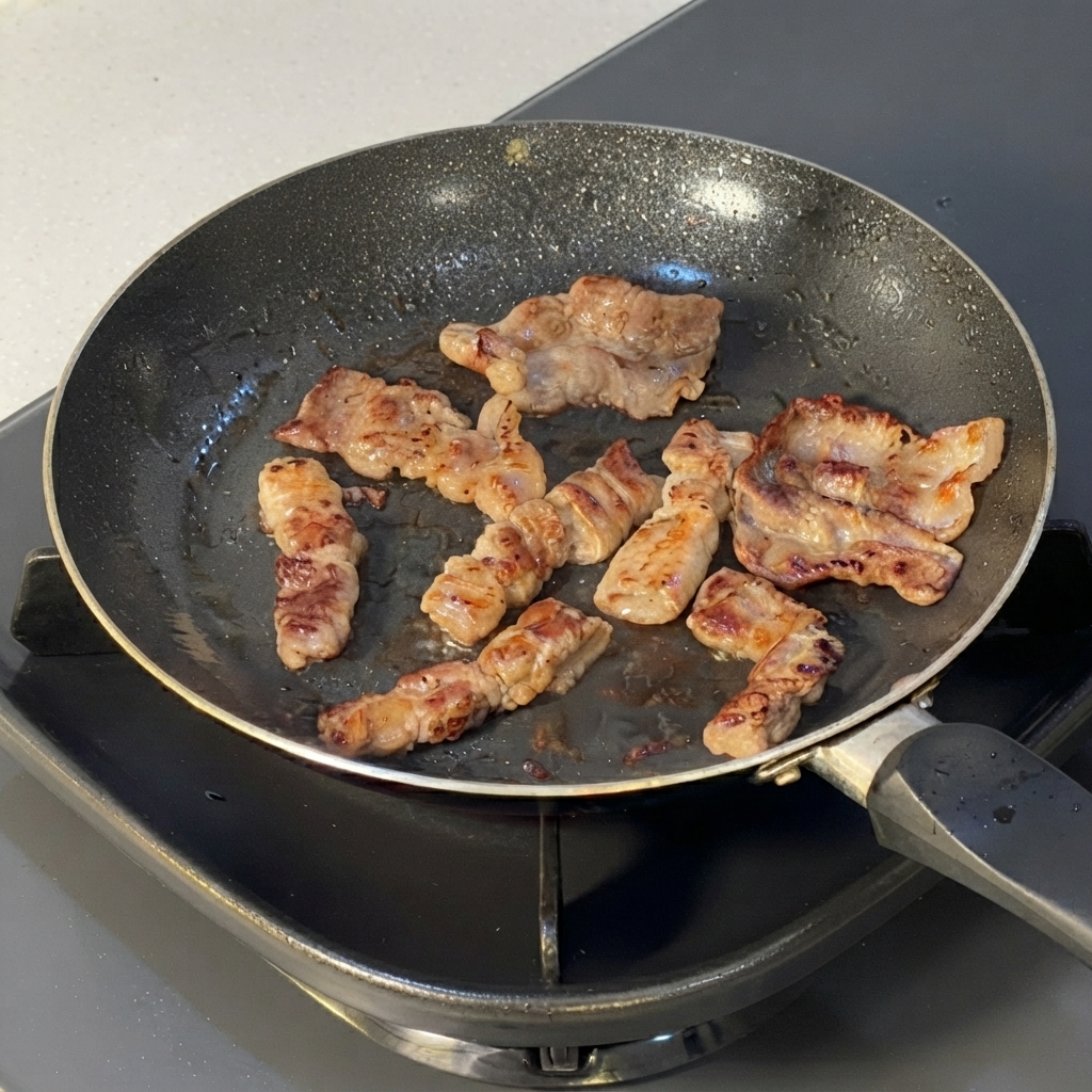 Filetes de ternera cocinados siendo cortados en segmentos más pequeños con tijeras de cocina dentro de una sartén.