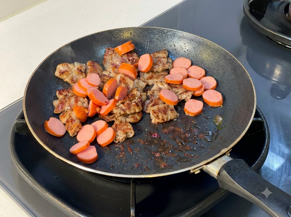 Rodajas de salchicha siendo añadidas a la sartén que contiene los filetes de ternera cocinados.