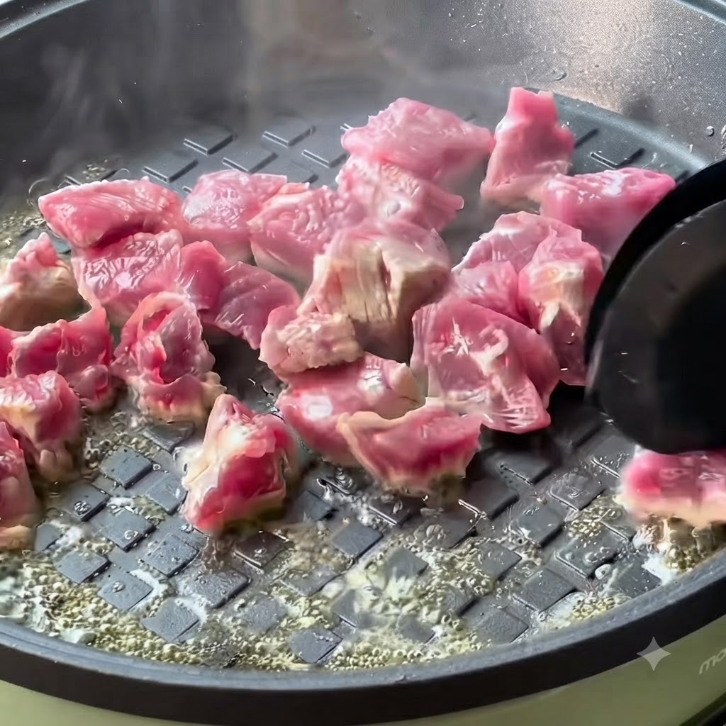 Cubos de ternera cocinándose y dorándose en una sartén caliente.