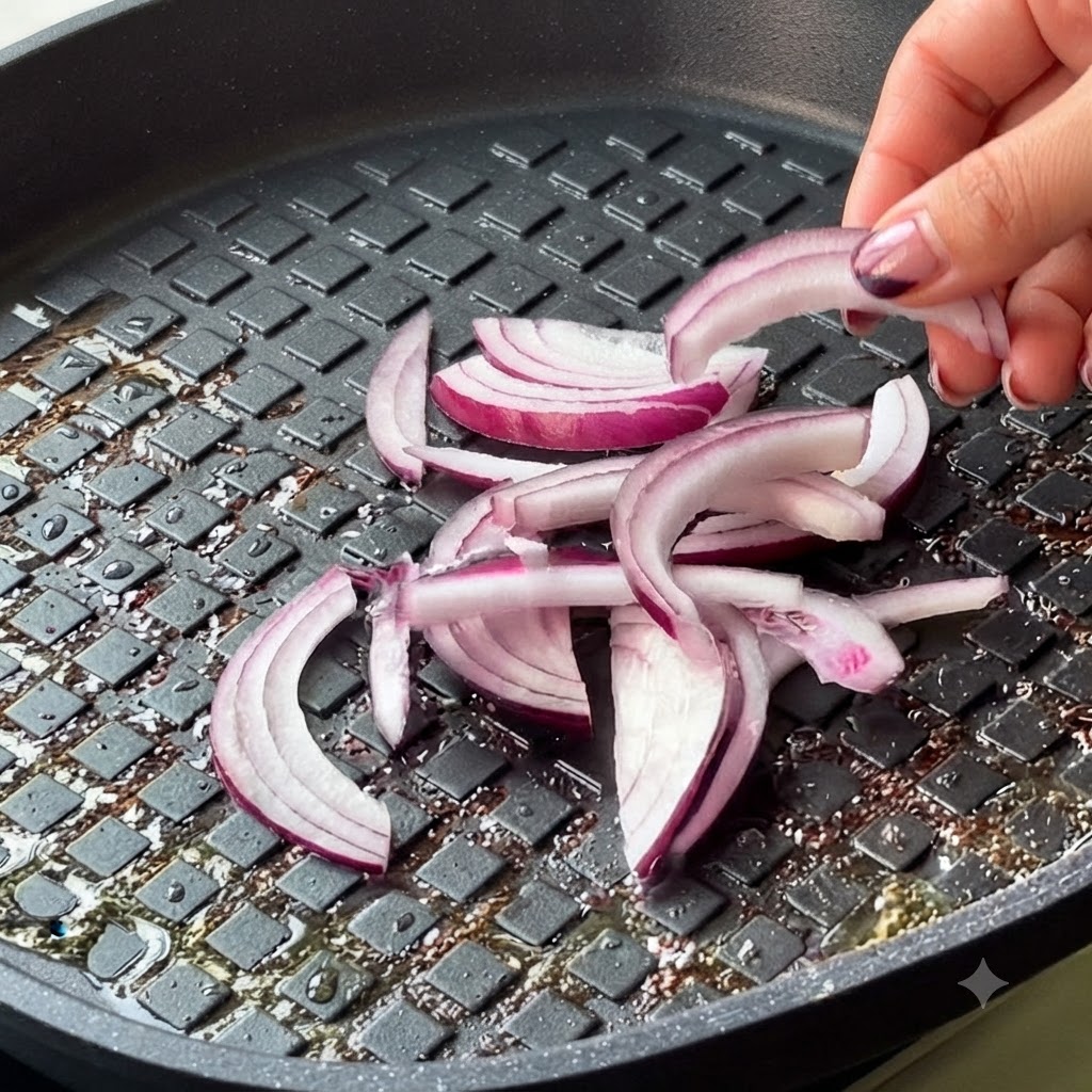 Cebolla morada en rodajas y kimchi siendo añadidos a la sartén.