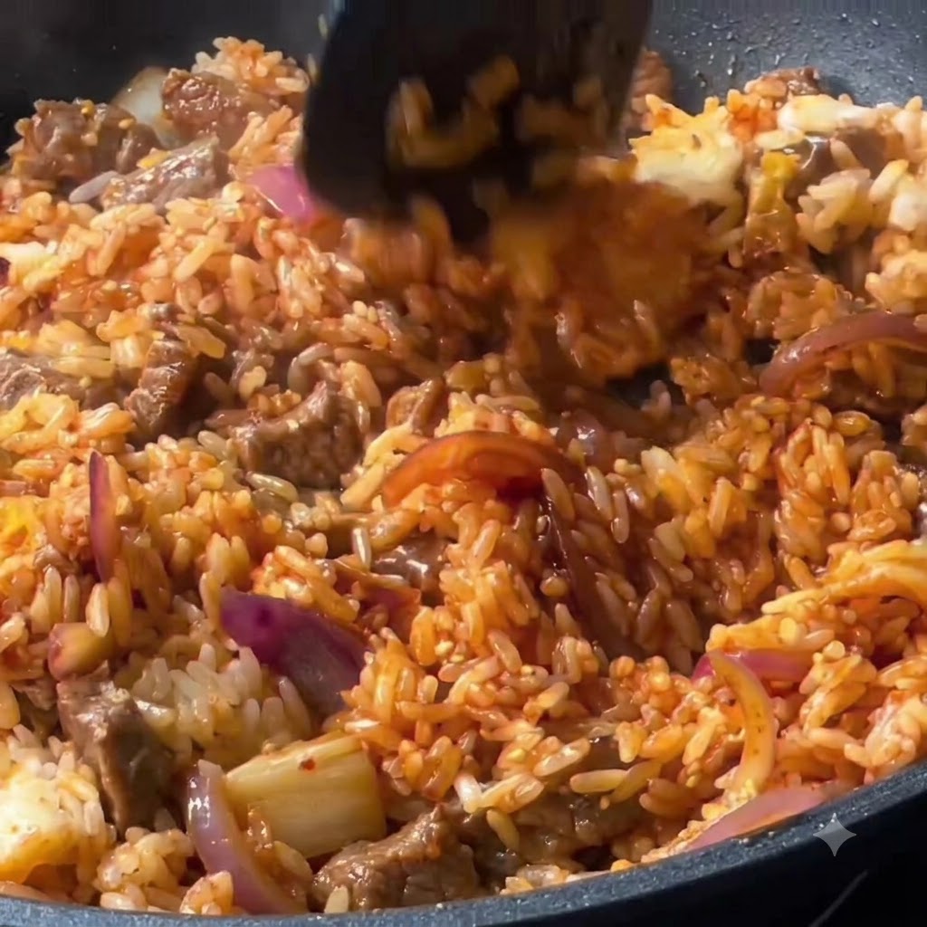 Arroz, ternera y verduras mezclándose a fondo con una espátula en la sartén.