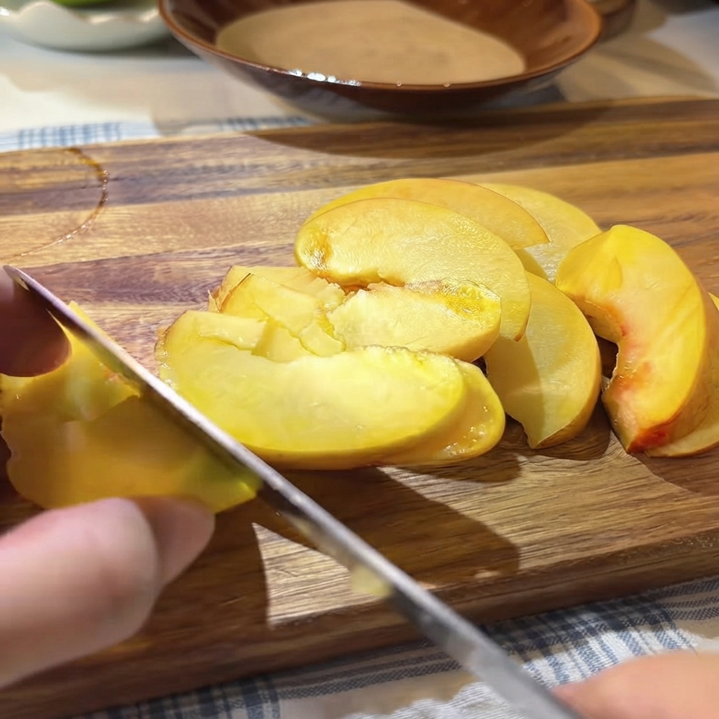 Semillas y pulpa de maracuyá fresca siendo vertidas con una cuchara sobre los duraznos amarillos cortados en la tabla de cortar.