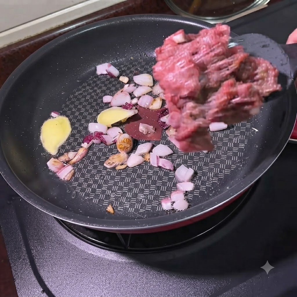 Carne molida siendo añadida con una espátula a una sartén que contiene cebollas sofritas y rodajas de jengibre.