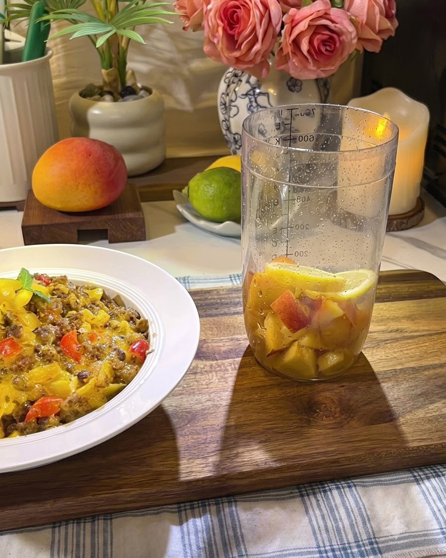 Ingredientes de fruta siendo presionados firmemente dentro de un vaso alto con un mortero.