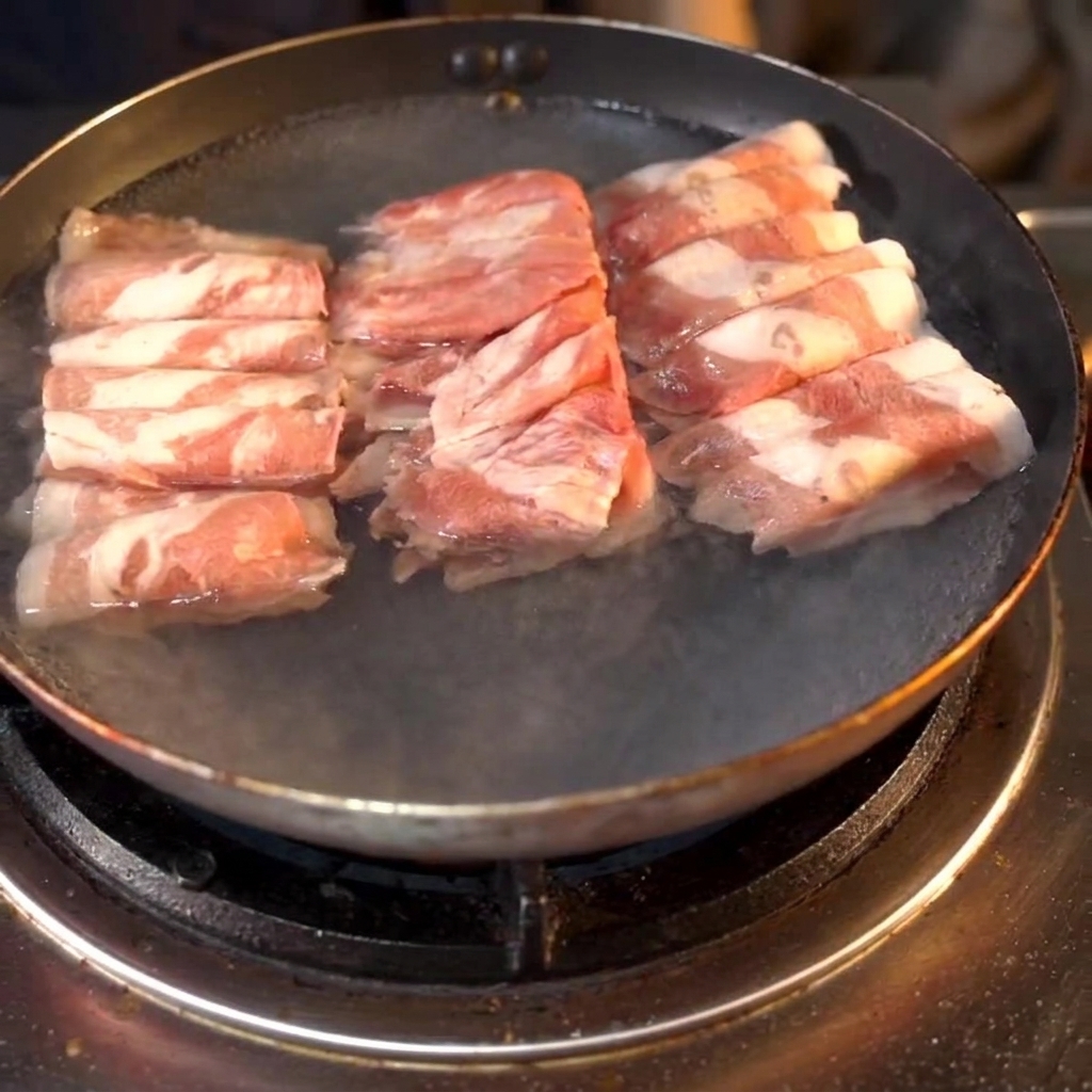 Rollos de ternera hirviendo en una sartén con vino para cocinar añadido al agua.